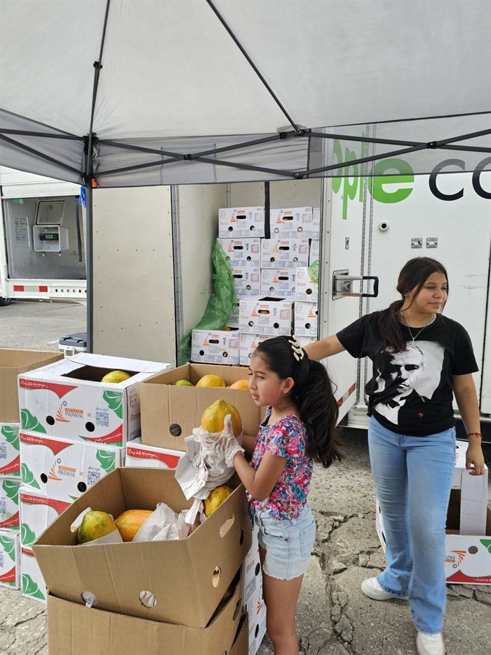 Volunteers handing a box of groceries to a visitor